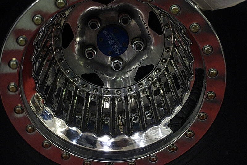 Close-up of a polished beadlock drag wheel showing the bolted beadlock ring around the outer flange