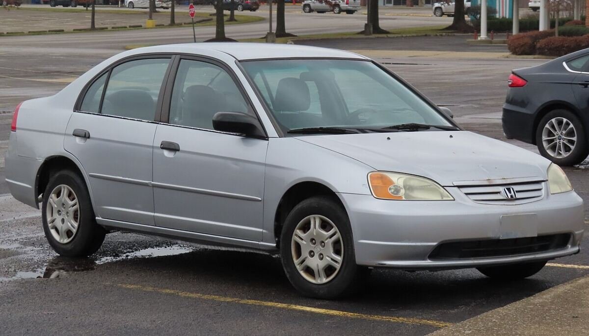 2001 Honda Civic LX sedan (7th generation) in silver on factory steel wheels with covers, front three-quarter view
