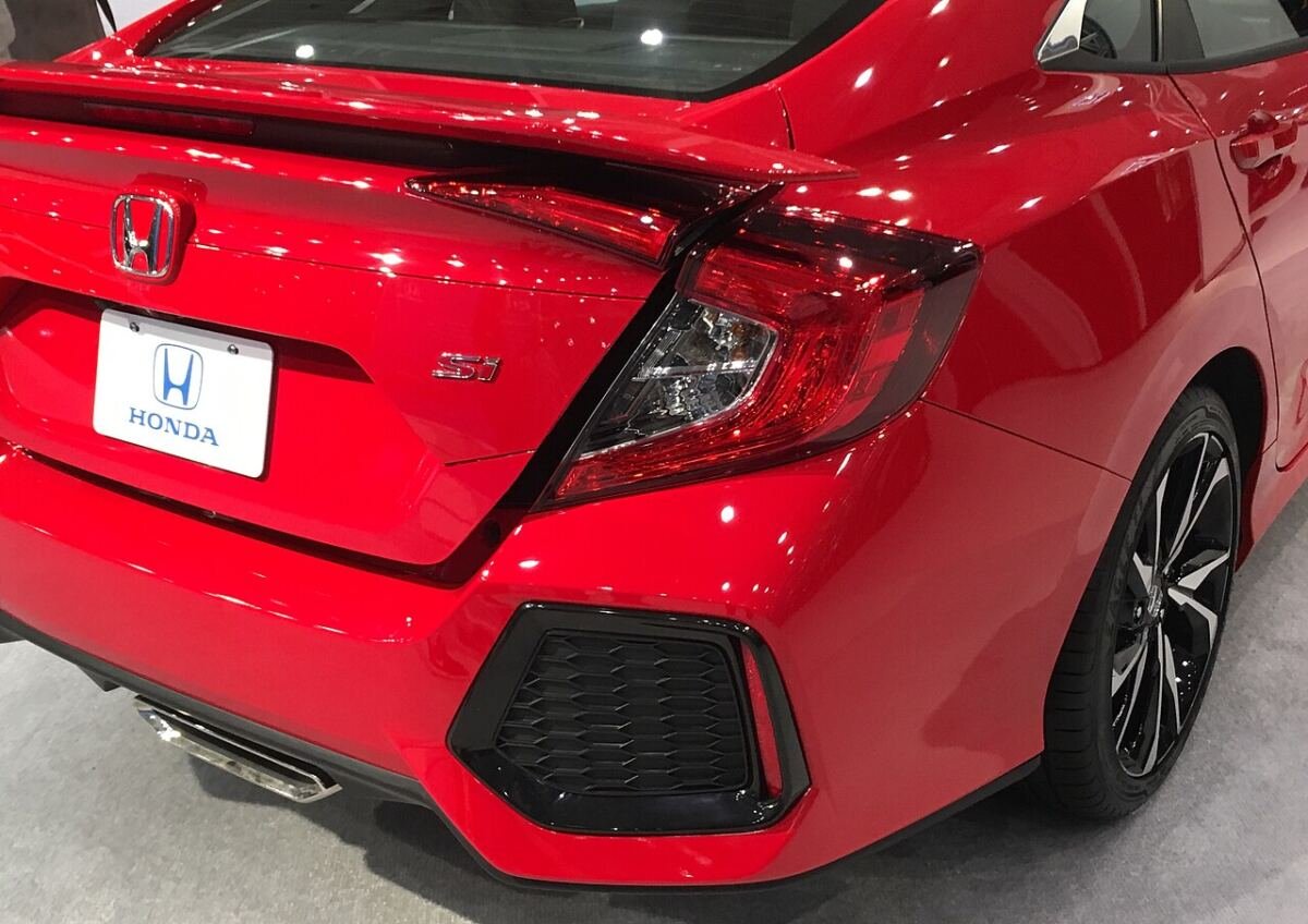 2019 Honda Civic Si sedan (10th generation) in red, rear three-quarter view with the 18-inch black wheel