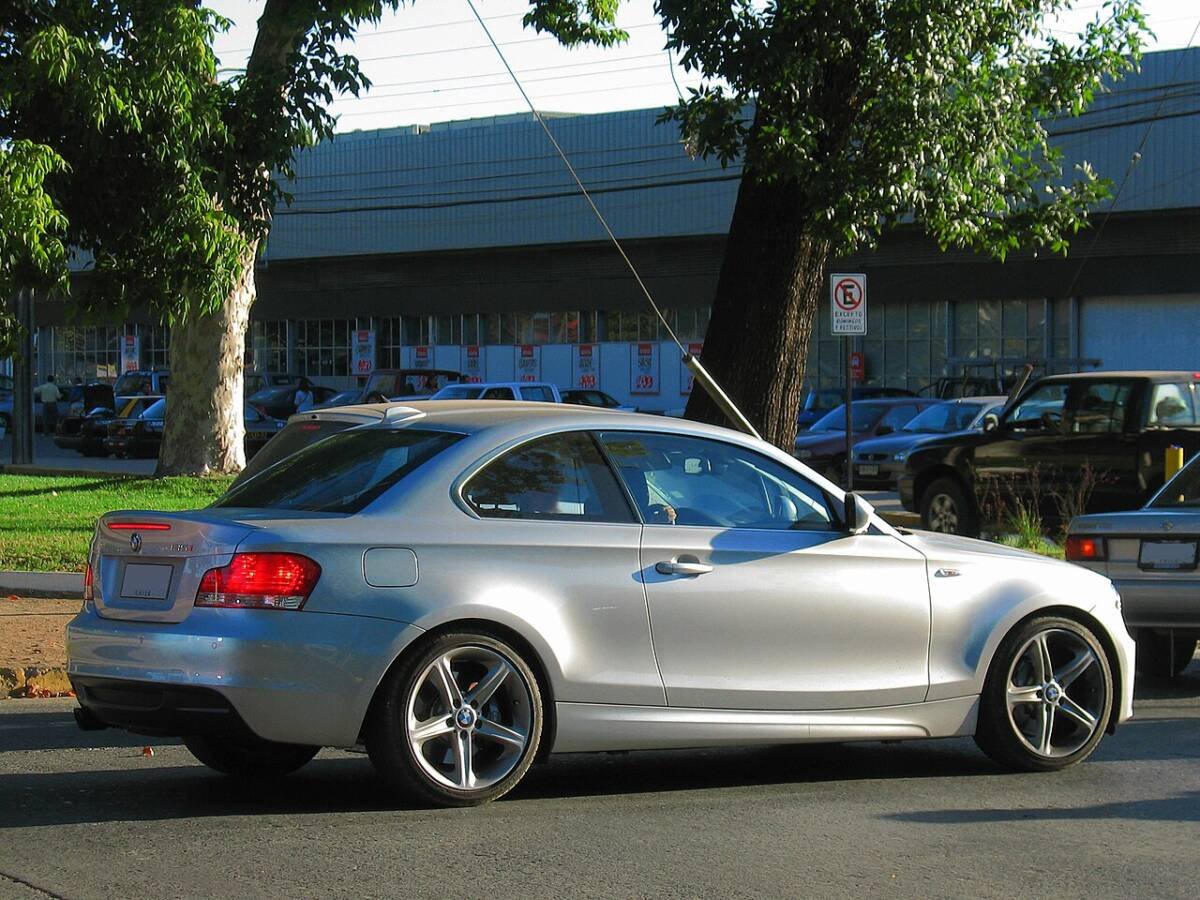 Silver BMW 135i Coupe E82 rear three-quarter view on factory 18-inch staggered double-spoke wheels
