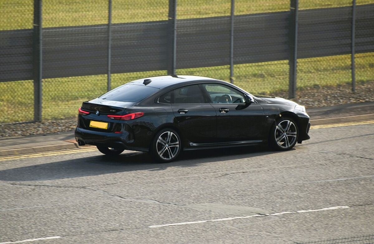 Black BMW 218i Gran Coupe (F44) with factory alloy wheels, rear three-quarter view