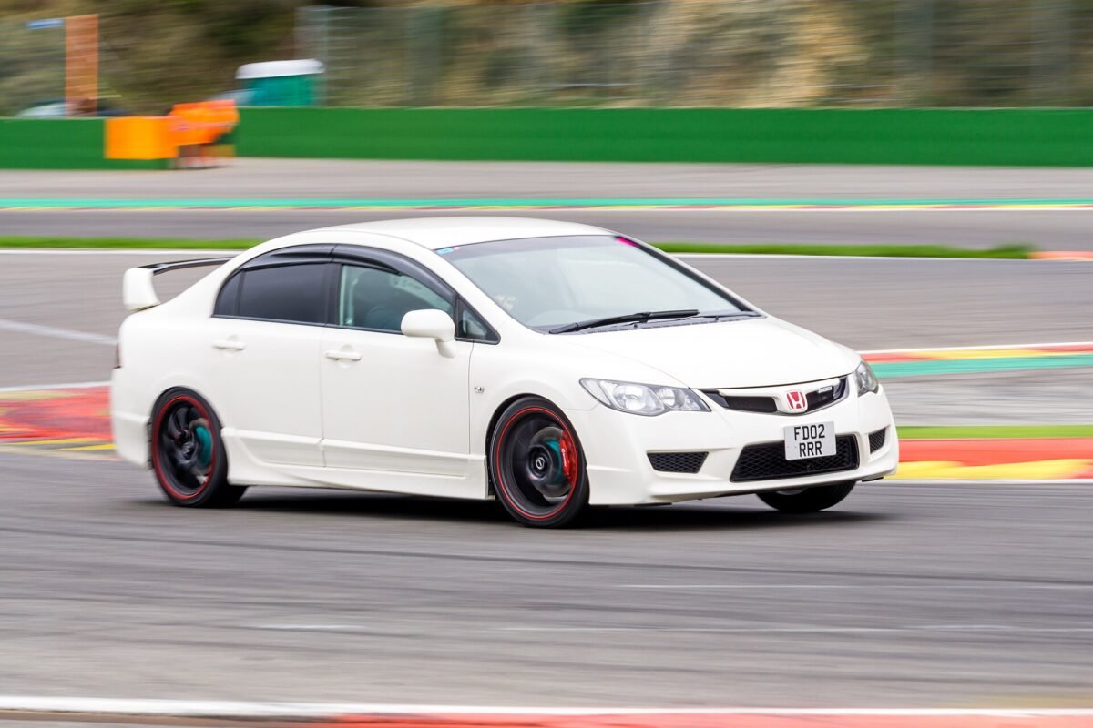 White Honda Civic Type R FD2 sedan cornering on a race track on aftermarket black wheels
