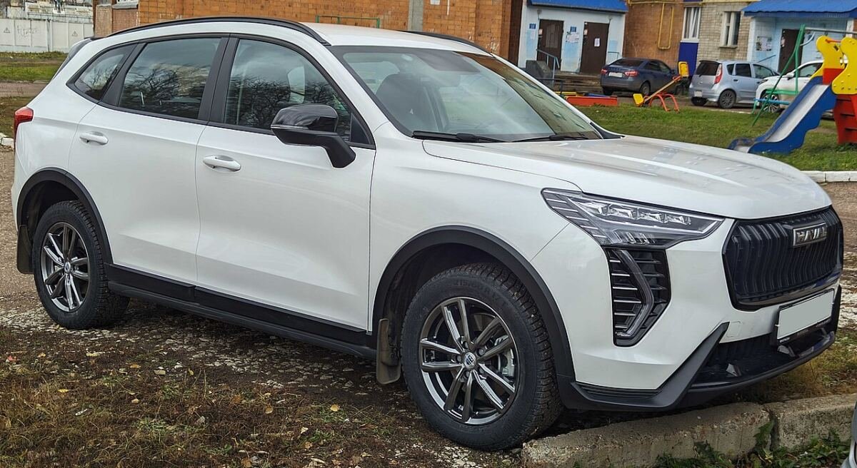 Белый Haval Jolion на парковке: штатные литые диски и профиль шины, вид спереди сбоку