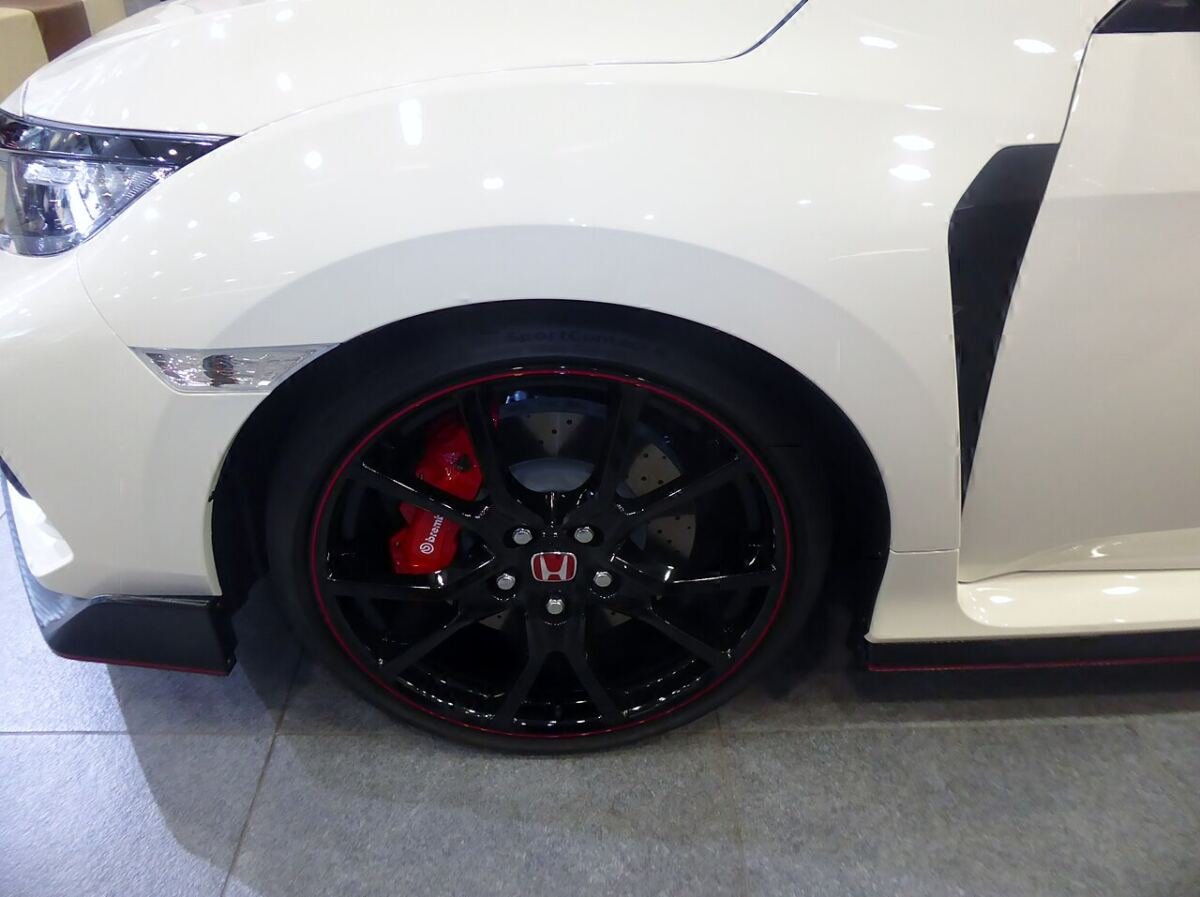 Front wheel of a Honda Civic Type R (FK8) with a black multi-spoke wheel, red Brembo caliper and Honda center cap