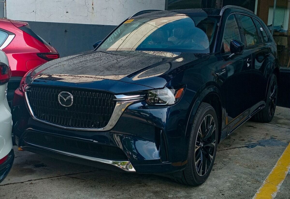 Mazda CX-90 three-row crossover in deep blue, front view with large factory alloy wheels