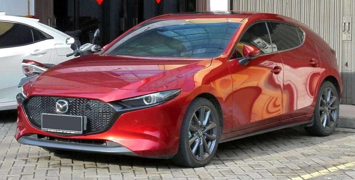 Fourth-generation Mazda3 (BP) hatchback in red, front left view with factory alloy wheels