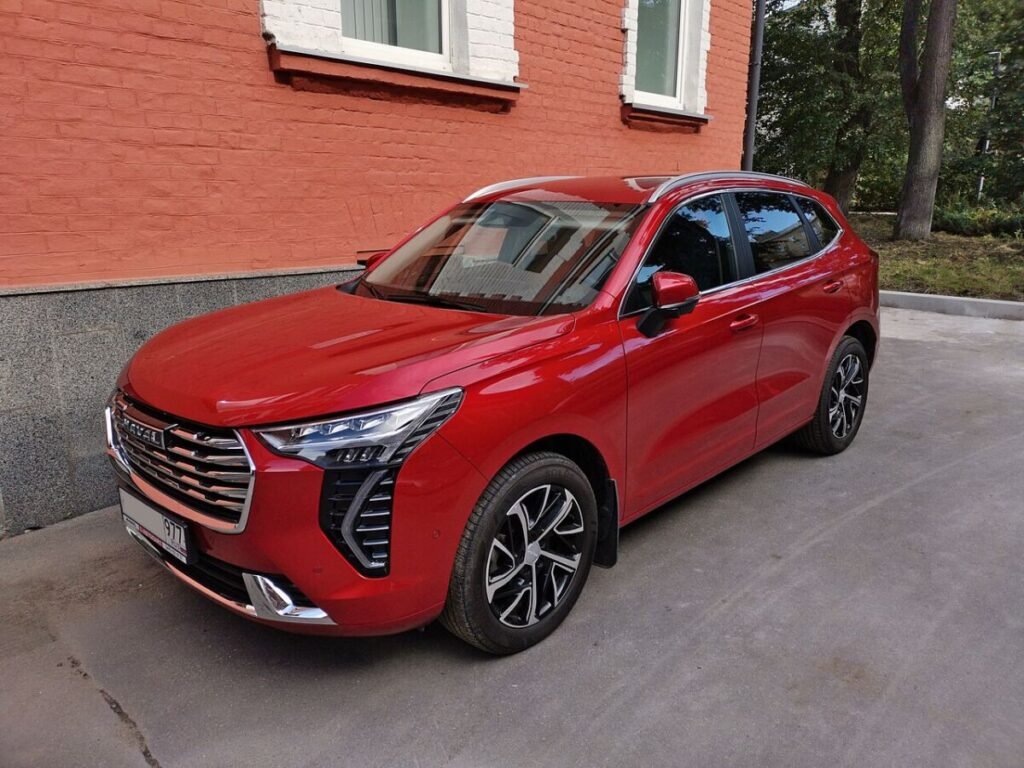 Зимние колёса на Haval Jolion: красный кроссовер со штатными литыми дисками, вид спереди
